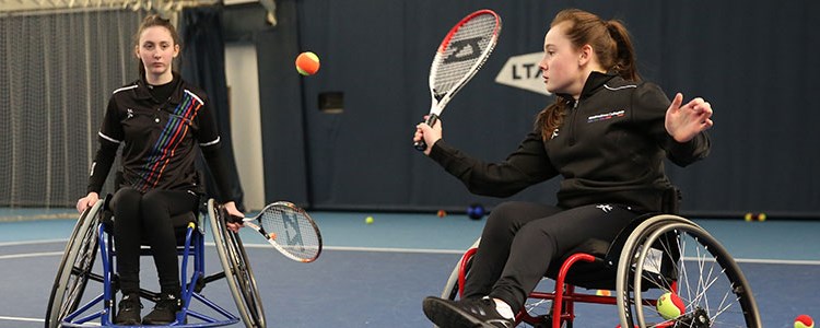 Two women playing wheelchair tennis