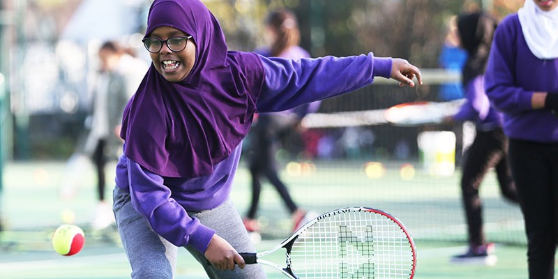 Young girl in purple top playing tennis