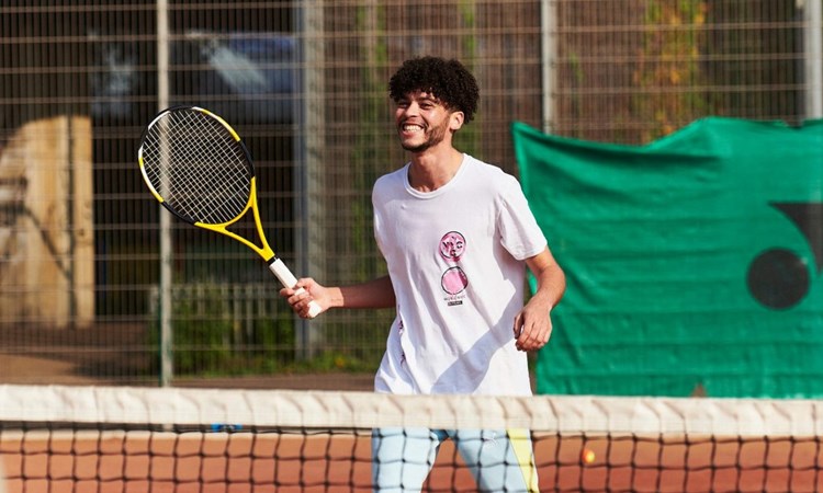 年轻男子在粘土网球场上玩得很开心