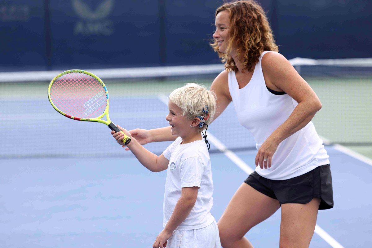 Young boy playing deaf tennis with a tennis coach