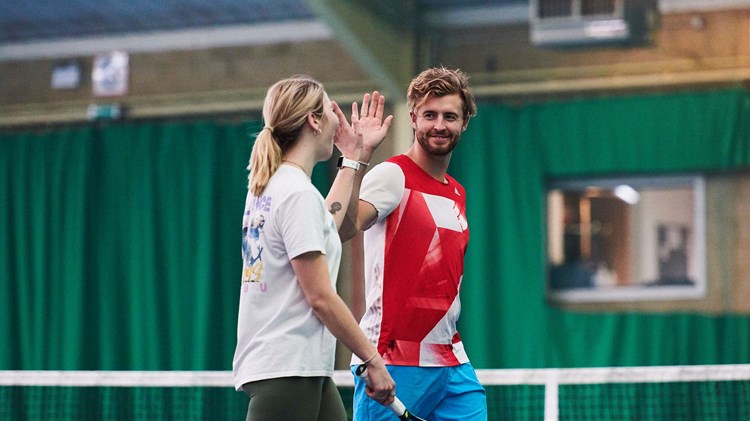 Man and woman high-fiving in front of tennis net