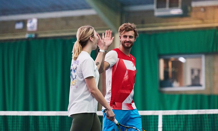 Man and woman high-fiving in front of tennis net