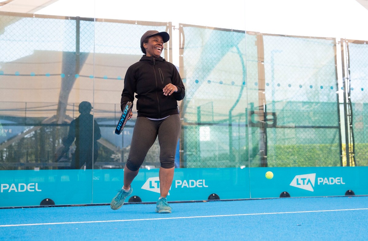 Female player laughing, holding a padel racket and standing in a padel court.jpg