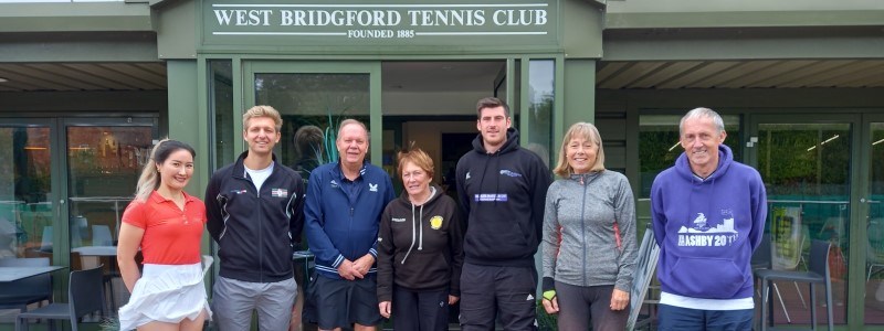 A small group of people smiling together in front of West Bridgford Tennis Club