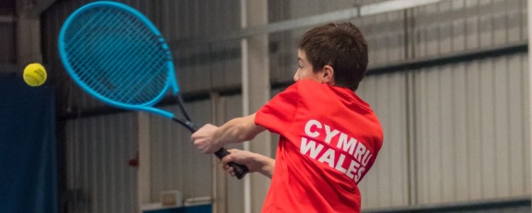 Aiden Coopman returning a shot in an indoors tennis match