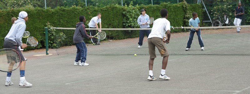 Kids playing tennis on an outdoor court