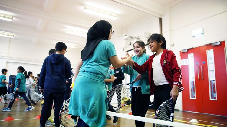 Female tennis instructor teaching a youth tennis lesson.