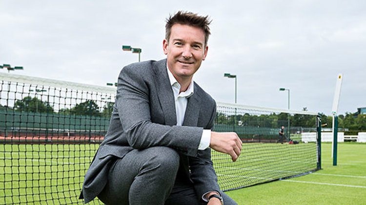 Scott Lloyd crouching down and smiling on a tennis court