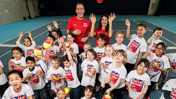 Large group of kids with tennis balls on a tennis court