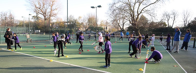 School children playing tennis  on outdoor courts