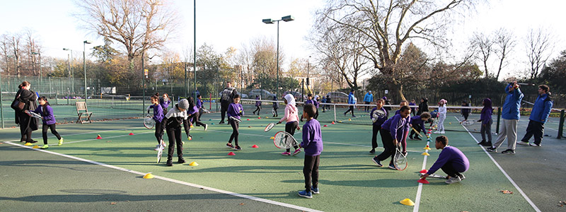 School children playing tennis  on outdoor courts