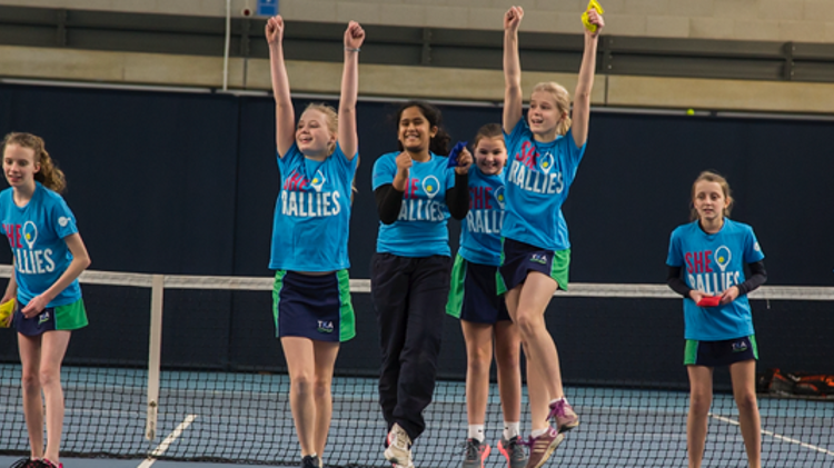 Group of girls cheering on a tennis court