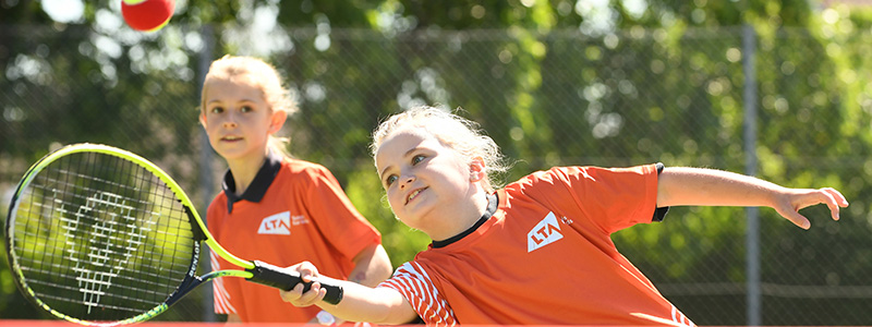 A child hitting a tennis ball as part of the tennis for kids programme