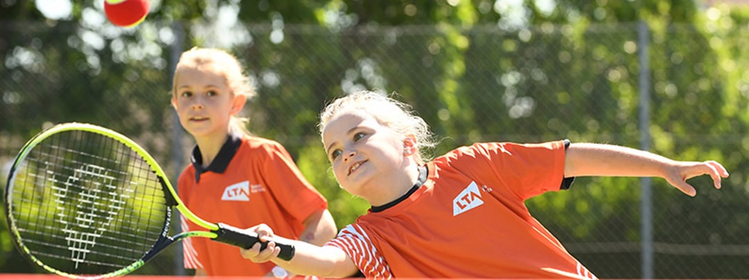 A child hitting a tennis ball as part of the tennis for kids programme