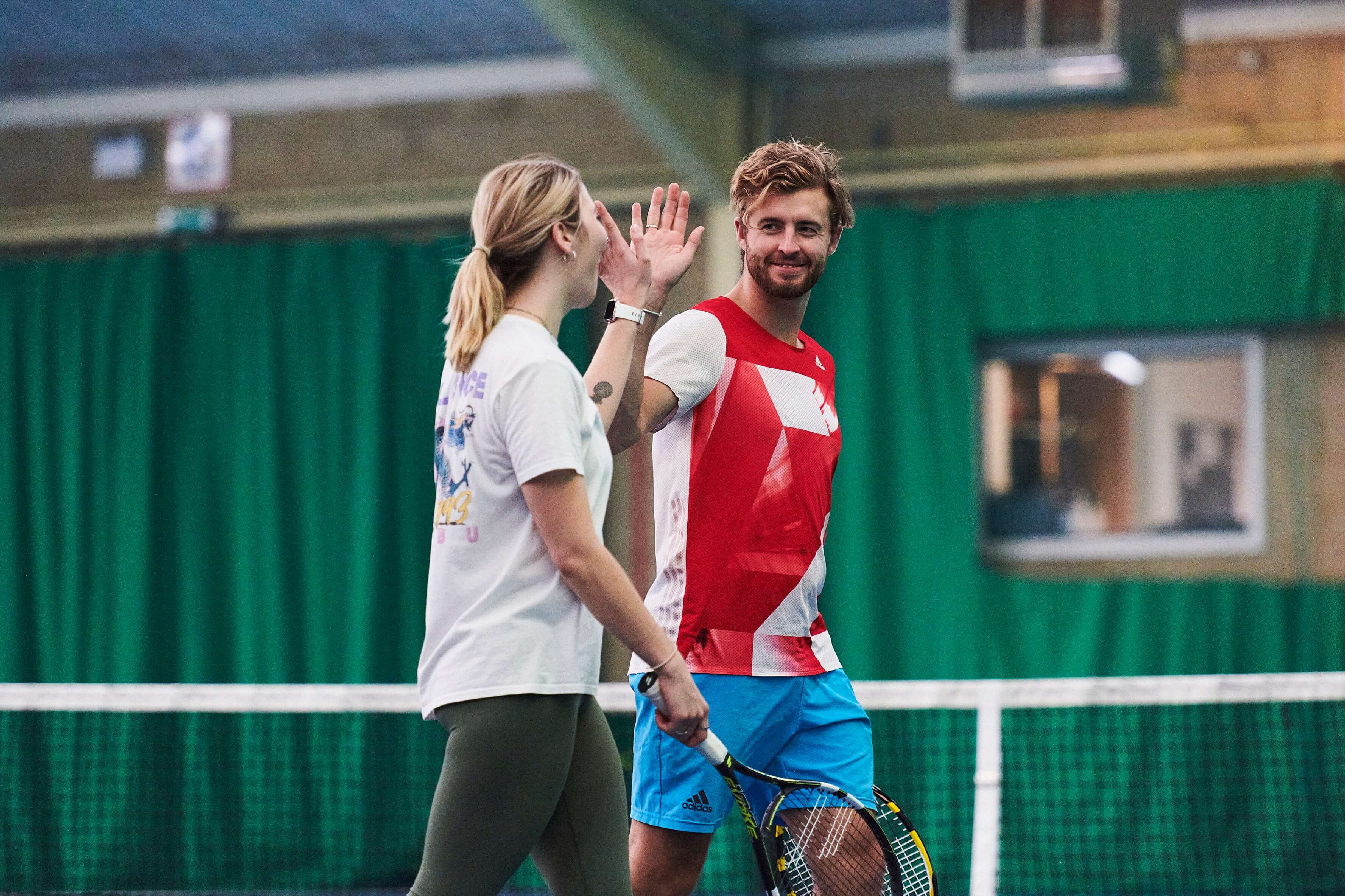 Man and woman high-fiving in front of tennis net