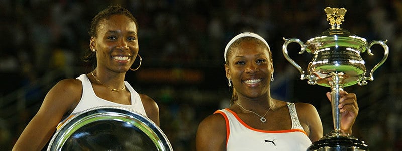 Serena and Venus Williams smiling with their trophies