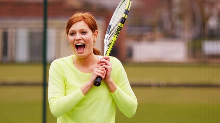 A women who is smiling and playing tennis