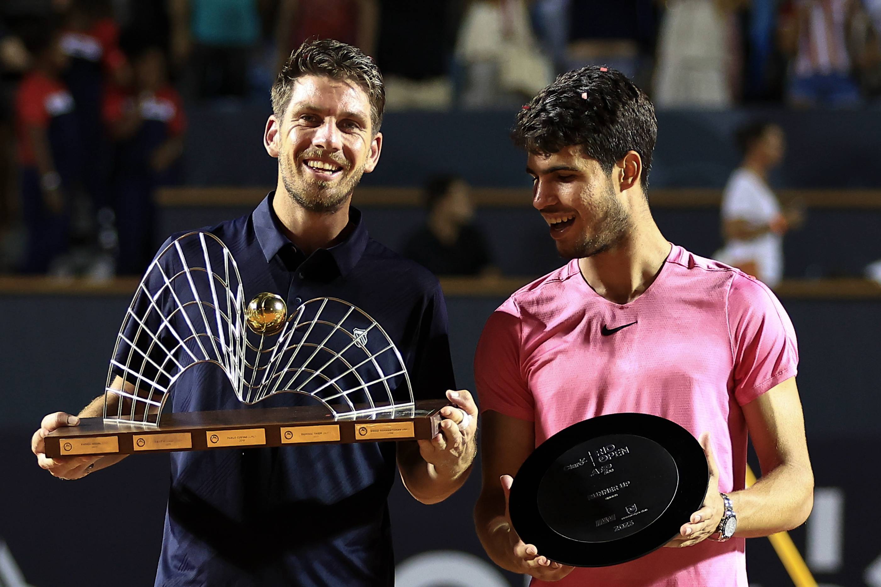 Cam Norrie holding the Rio Open title next to Carlos Alcaraz