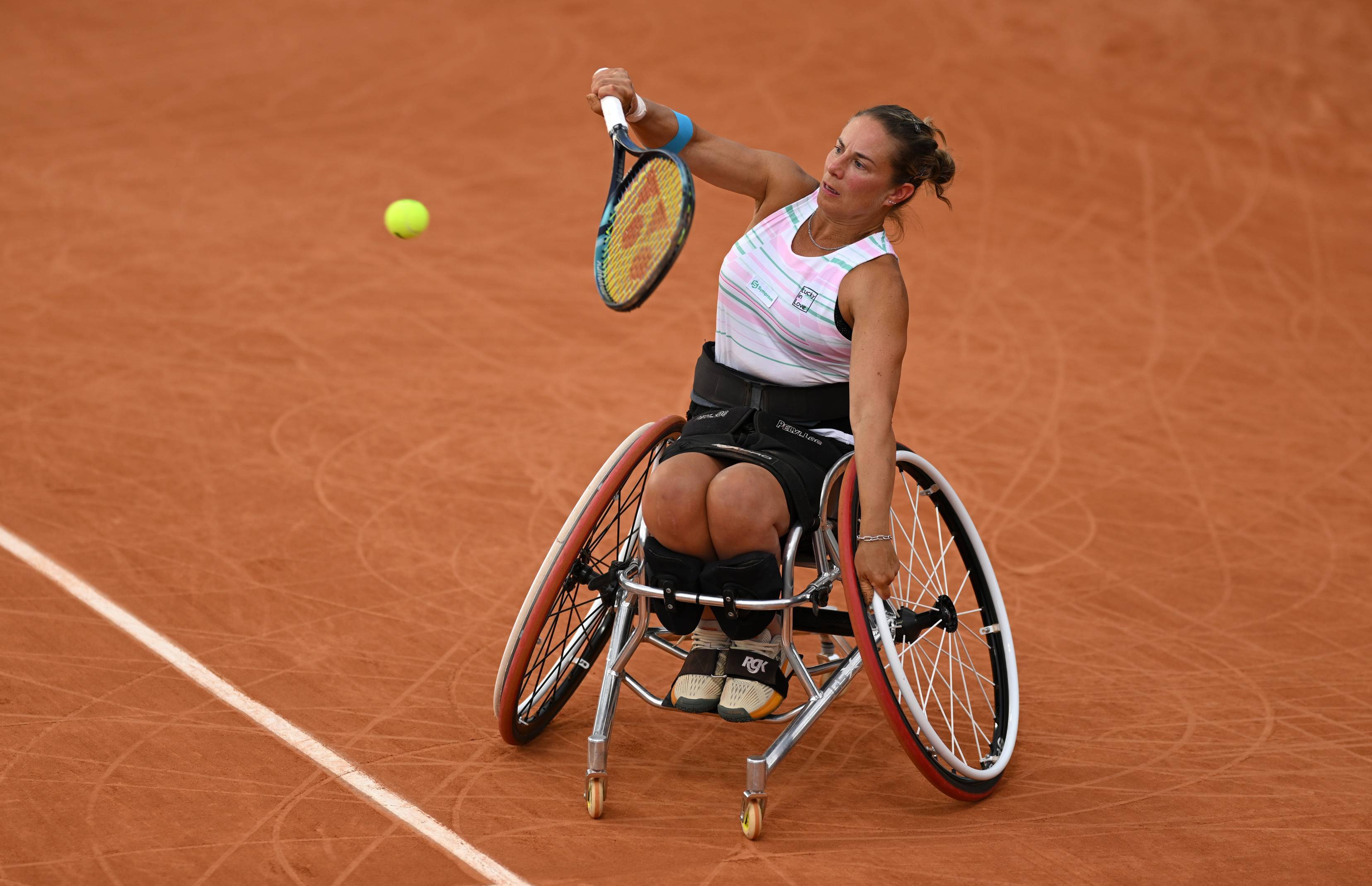 Wheelchair tennis player Lucy Shuker hitting a backhand on a clay court while sat in her wheelchair 