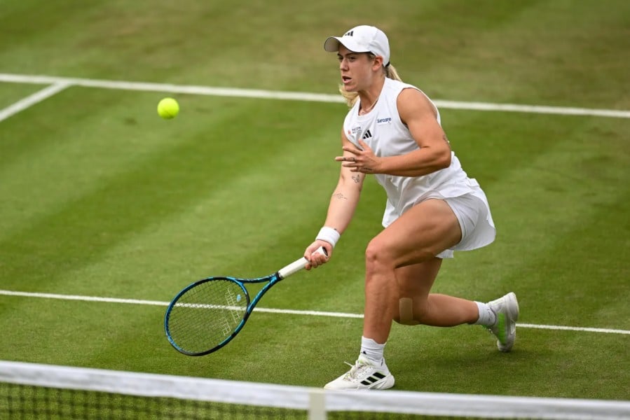 Sonay Kartal preparing to hit a volley at the net on a grass court
