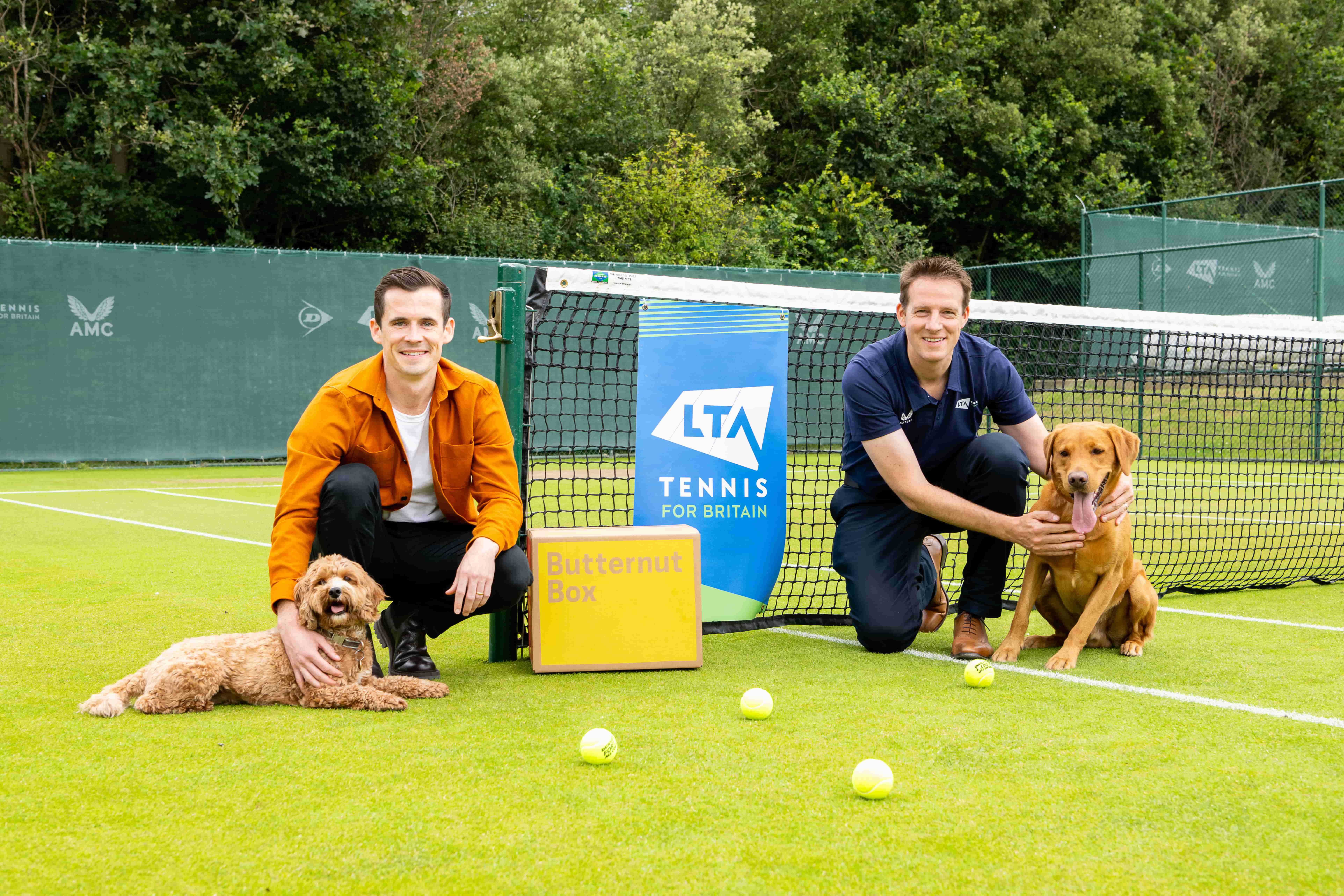 LTA partners Butternut Box on a tennis court with two dogs and a box of their freshly made dog food