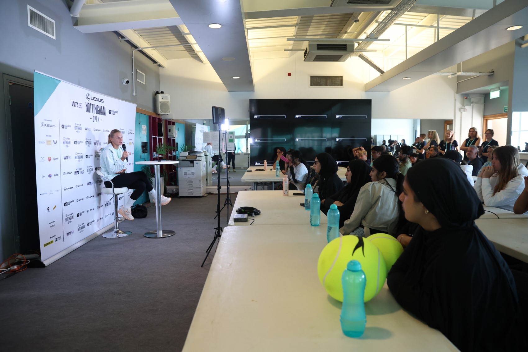 Player sits at table with children at row of tables listening
