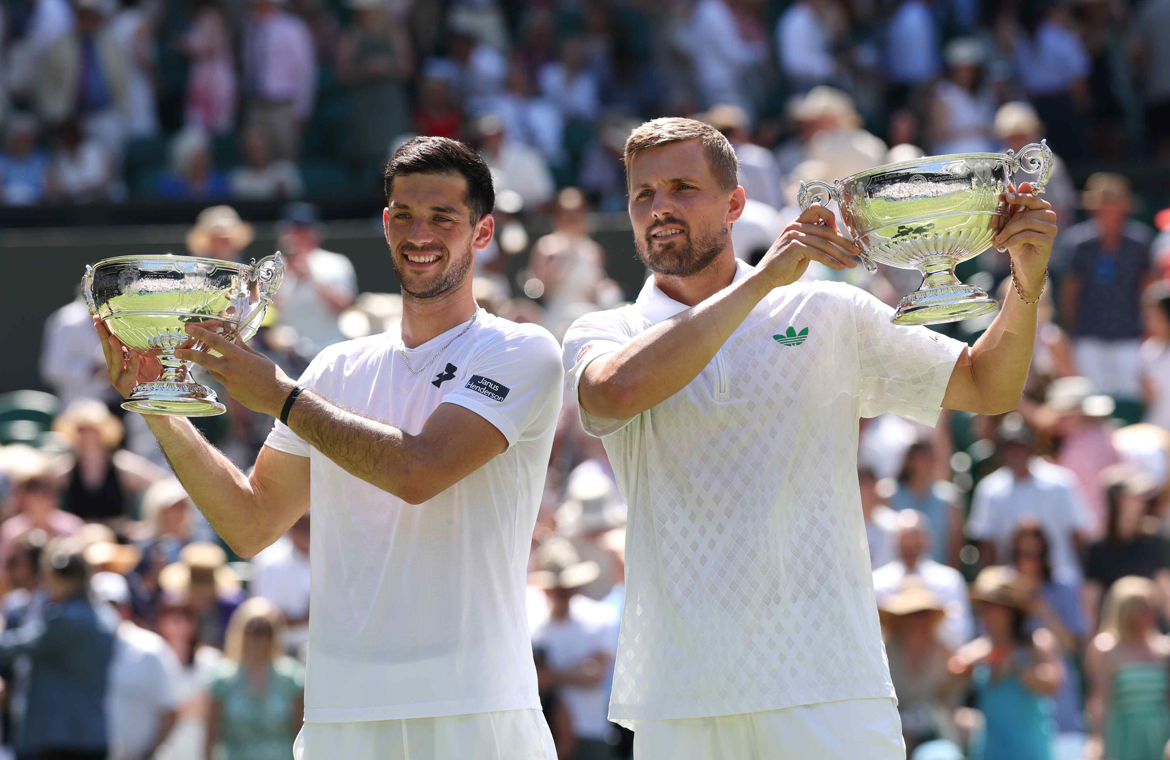 British doubles duo Julian Cash and Lloyd Glasspool smiling while holding their men's doubles Wimbledon title