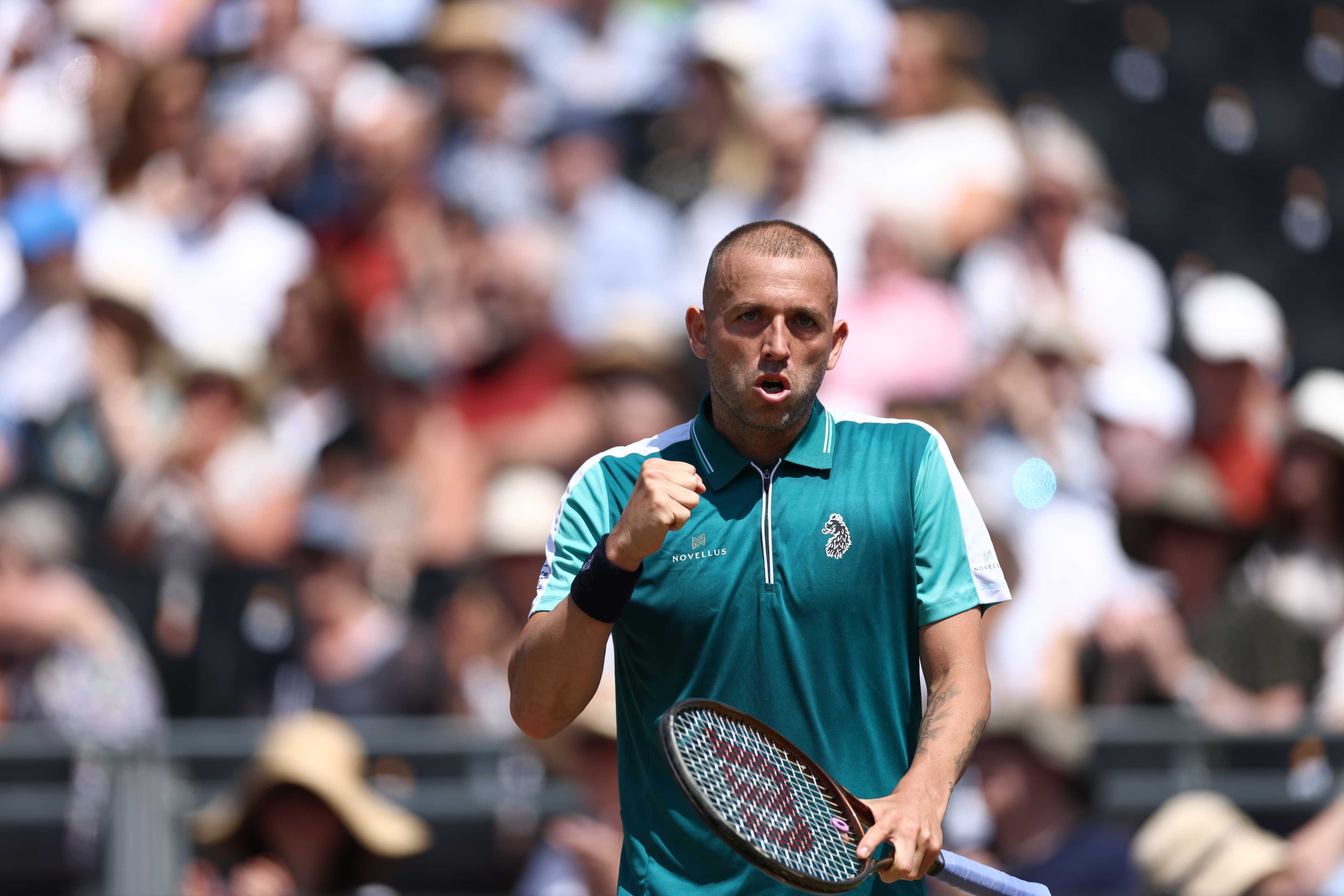 Dan Evans fist pumping in celebration while holding his racket in his other hand