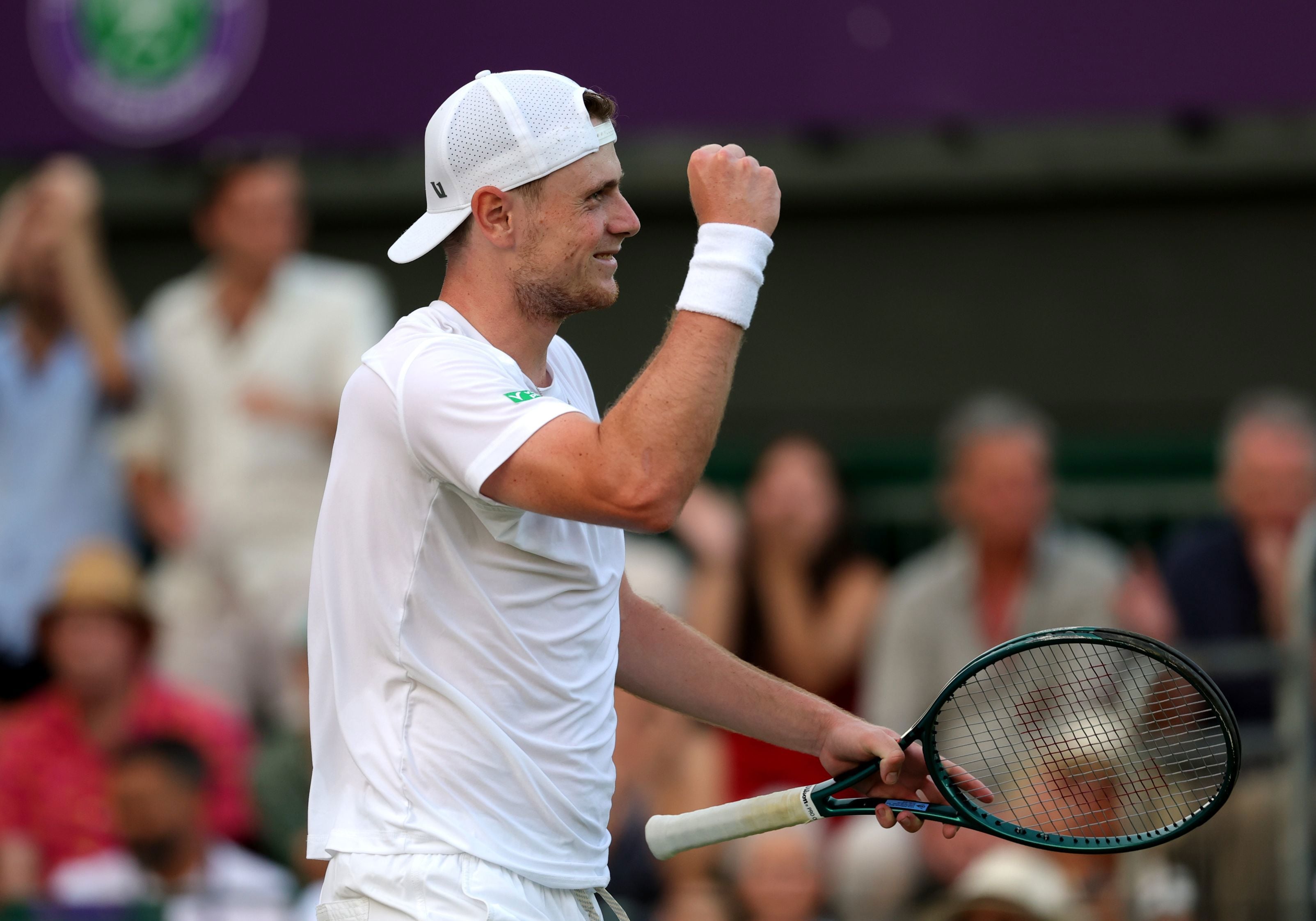 Jack Pinnington Jones smiling while holding his tennis racket after winning his first round match at Wimbledon