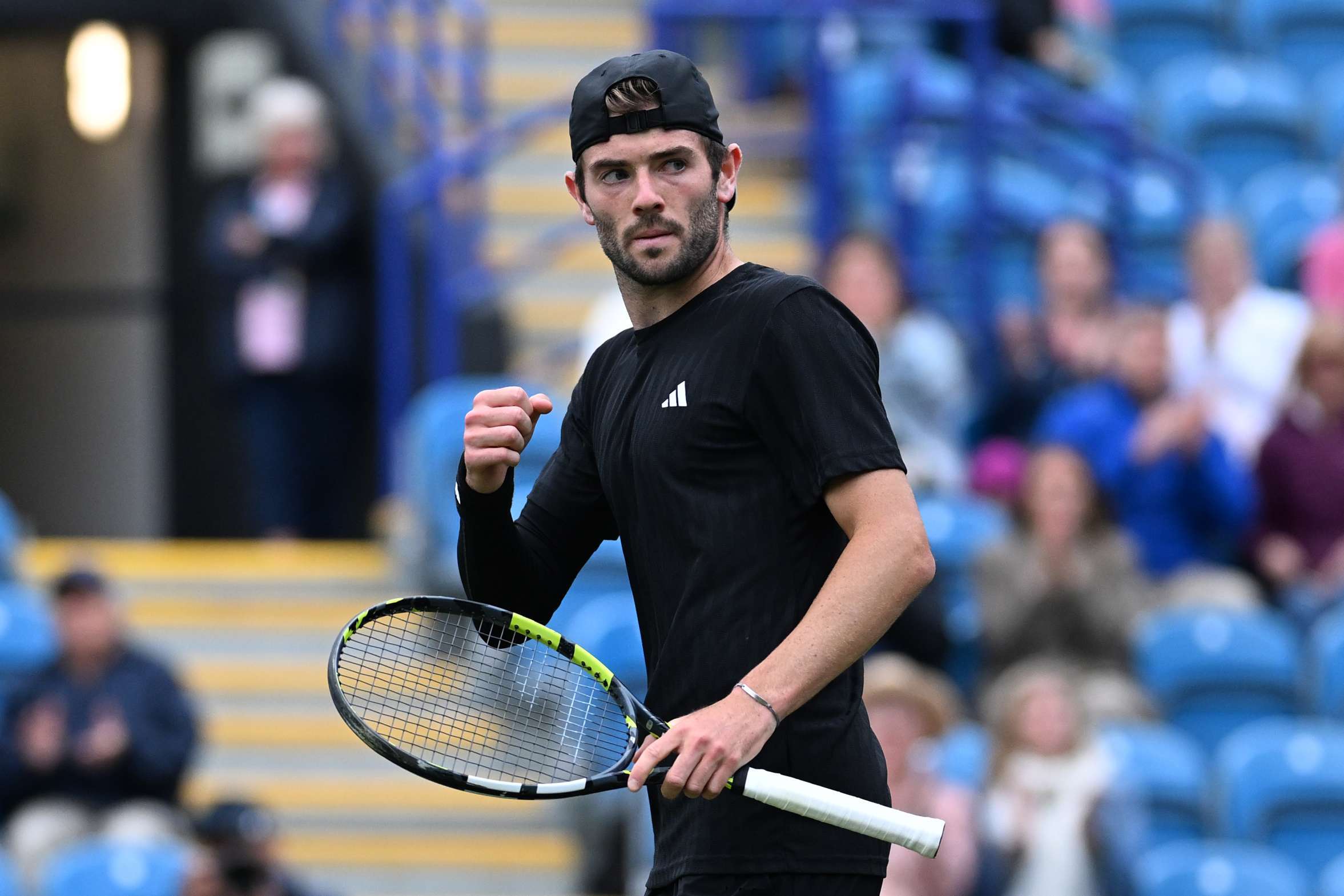 British tennis player Jacob Fearnley holding his tennis racket in one hand and clenching his fist in the other at the Lexus Eastbourne Open
