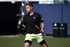 British tennis player Neal Skupski clenching his fist and holding his tennis racket in one hand while on court at the Lexus Eastbourne Open