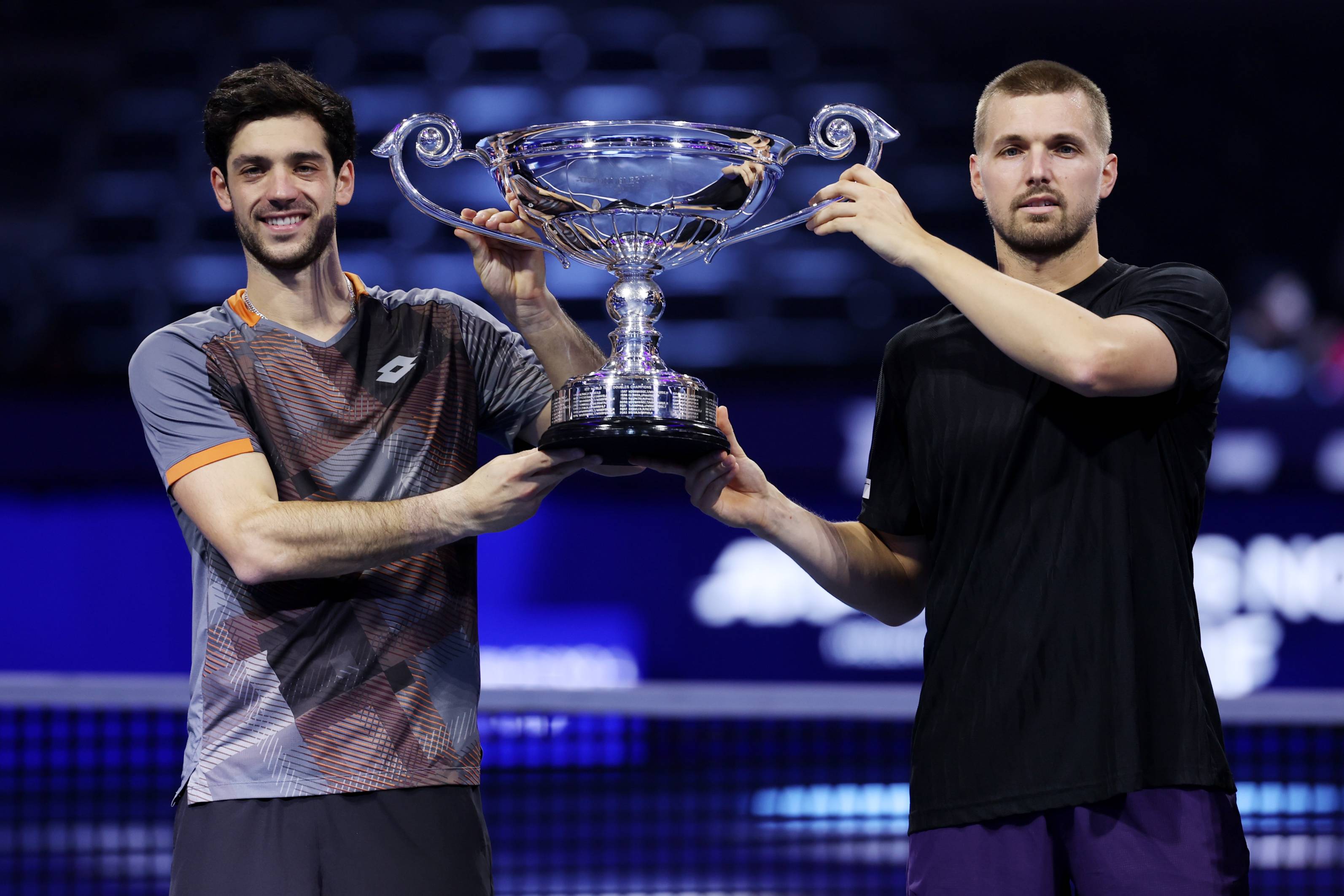 Julian Cash and Lloyd Glasspool smiling while holding the ATP year-end doubles No.1 trophy on court at the Nitto ATP Finals