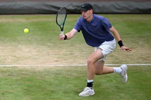 Ben Jones crouching down to hit a forehand on a tennis court at the HSBC Championships