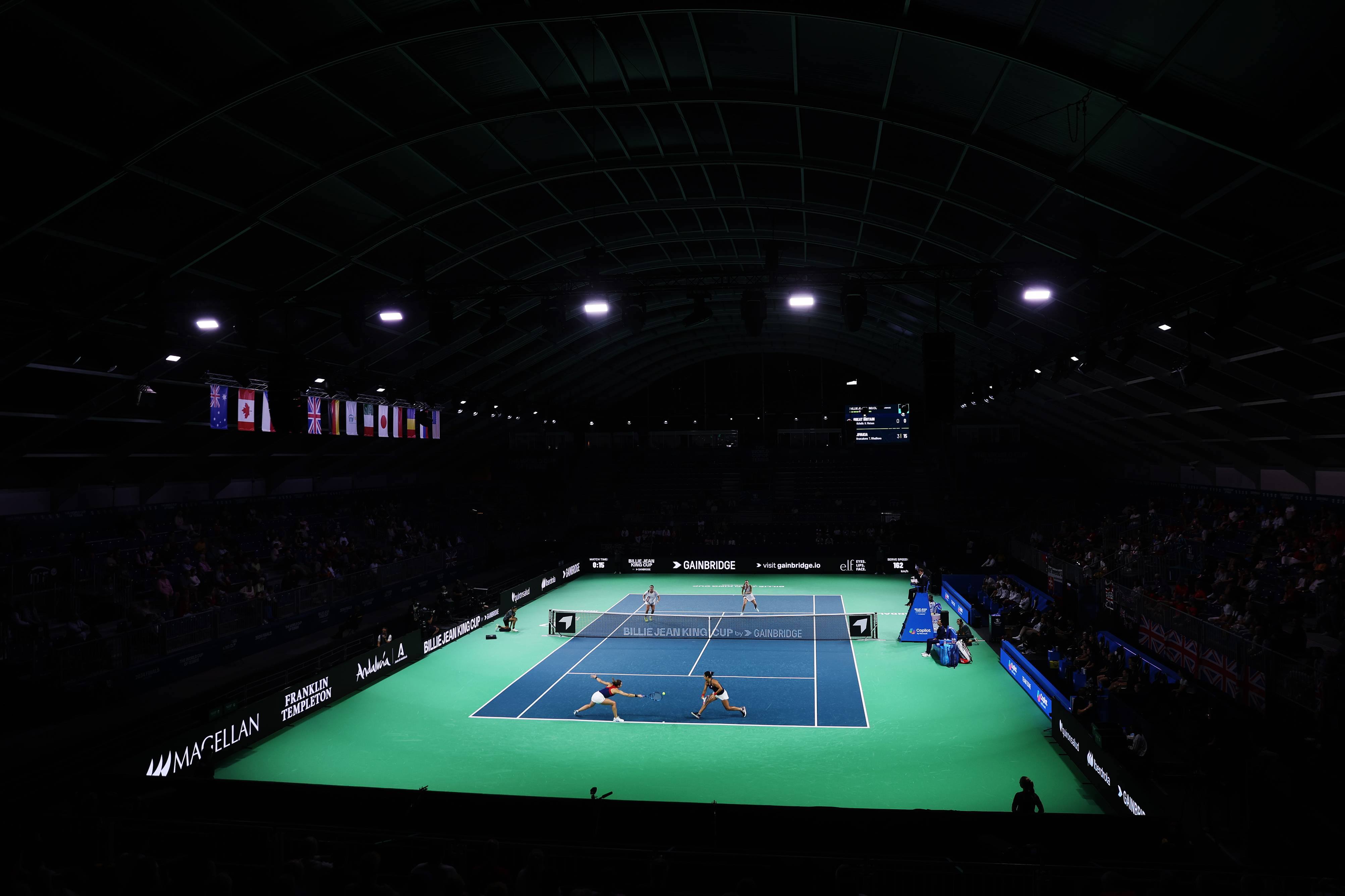 A doubles match taking place on the lit up Billie Jean King Cup Finals court