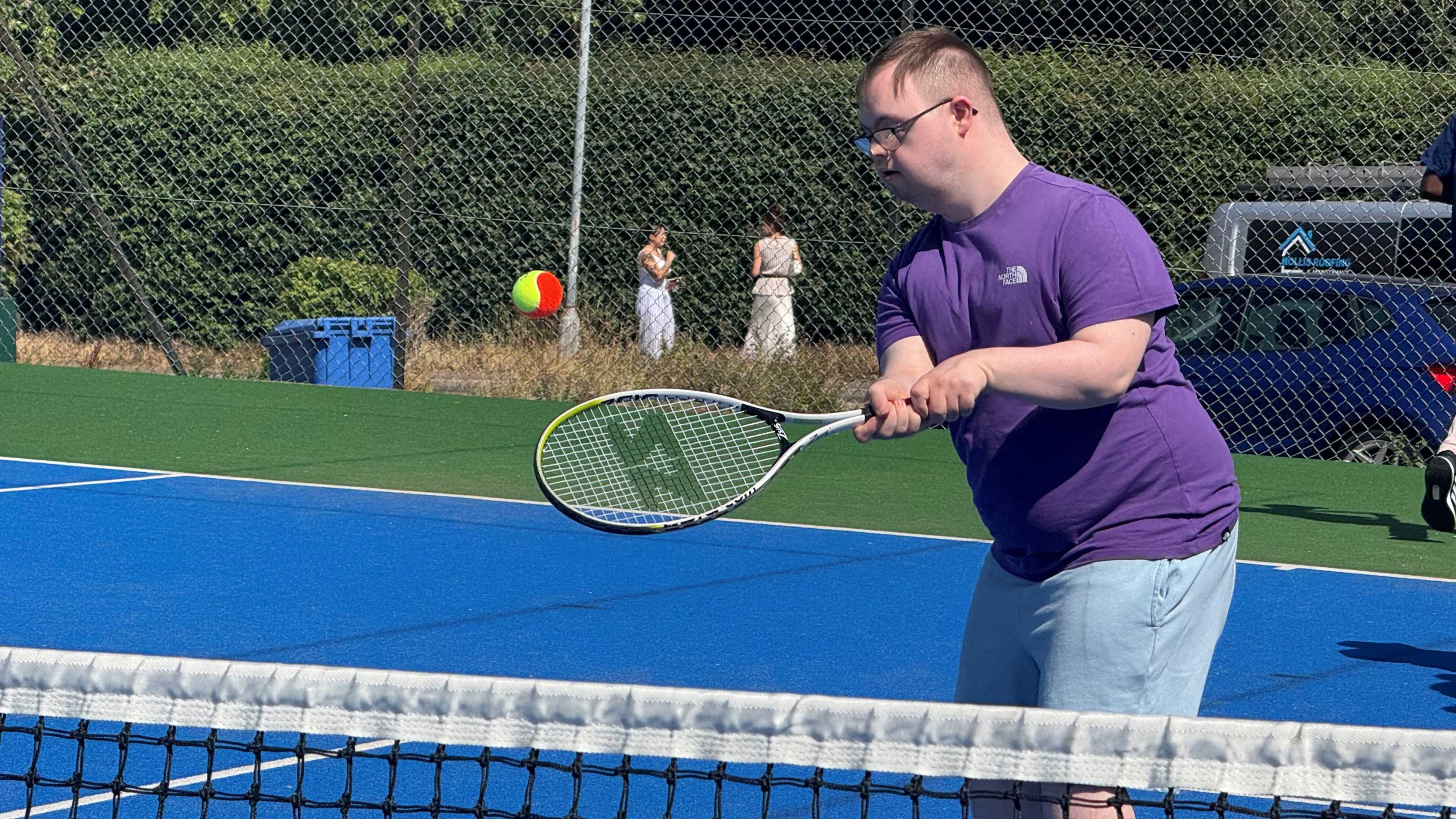 A participant volleys a ball over the net