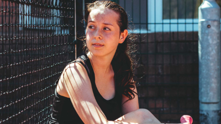 alanna sitting on the floor of the tennis court looking away