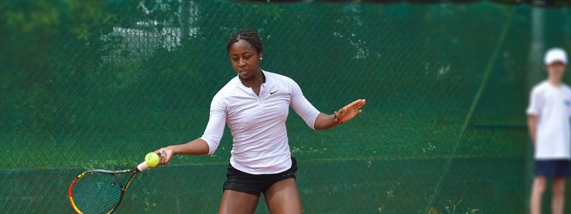 Woman playing tennis with a person in the background