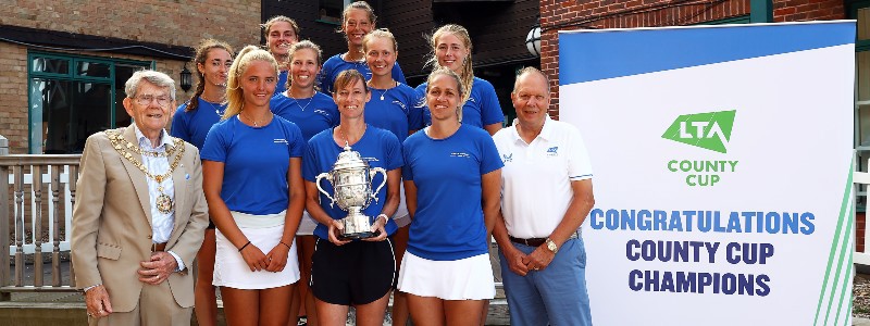 The Herefordshire ladies team standing in a group smiling and holding the County Cup Trophy