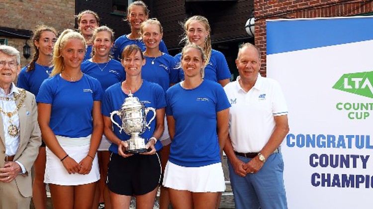 The Herefordshire ladies team standing in a group smiling and holding the County Cup Trophy