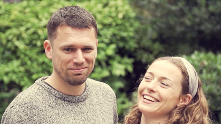 close up image of steve and elle standing together with steve smiling and elle laughing
