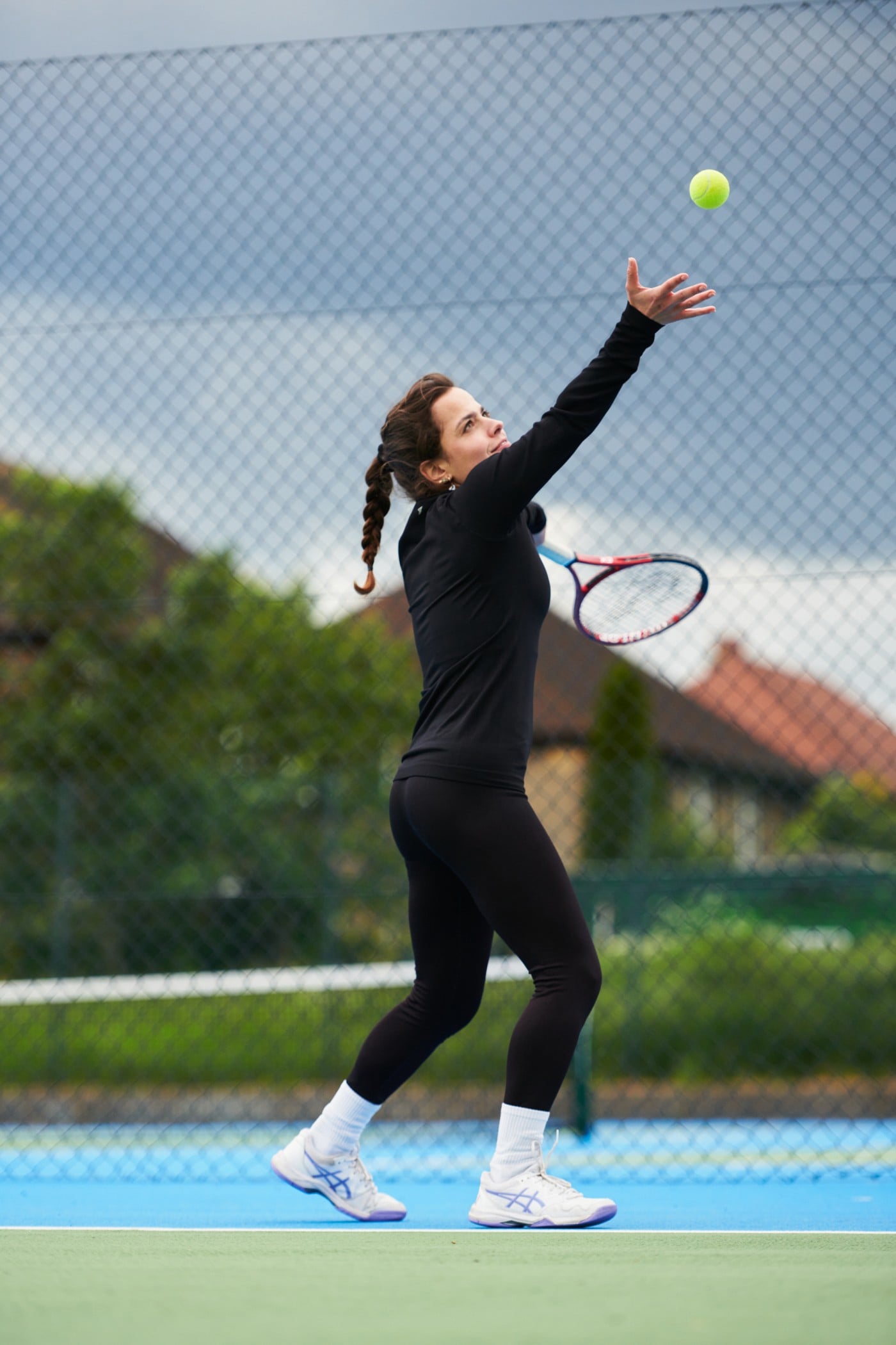 Woman throwing the tennis ball up to serve.