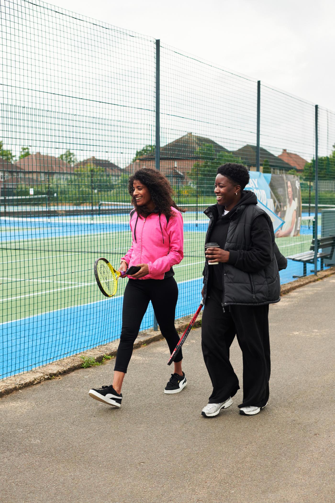 Two women walking to to the tennis court.
