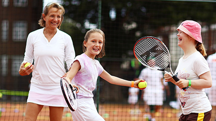 Young girls smiling and laughing playing tennis