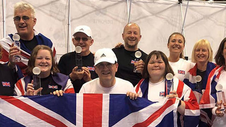 GB players holding winning trophies in hand and four of the players holding a large GB flag at the front