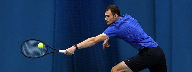adult player on court reaching out to hit a ball