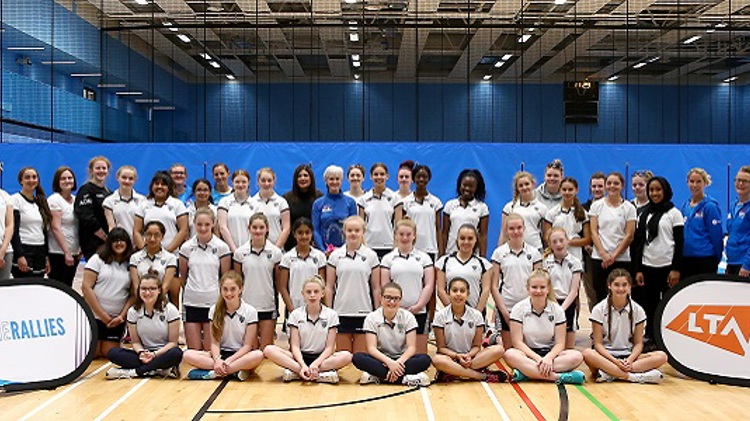 Judy Murray standing alongside girls tennis players smiling for a group picture with the LTA She Rallies banner