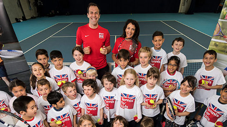 Group of children on a tennis court holding a tennis racket and ball