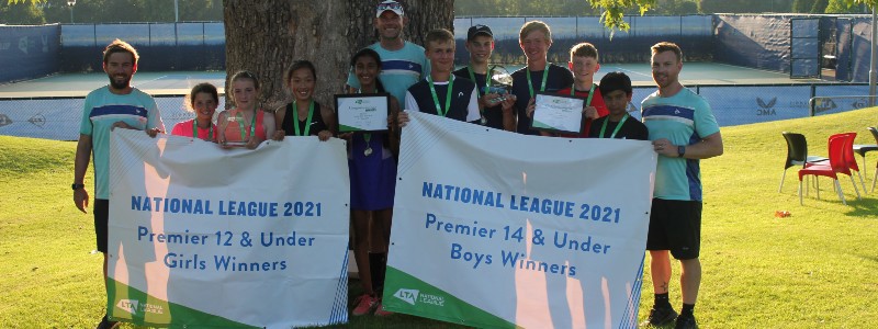 12U girls and 14U boys winning teams standing in a line holding the National League 2021 winners signs