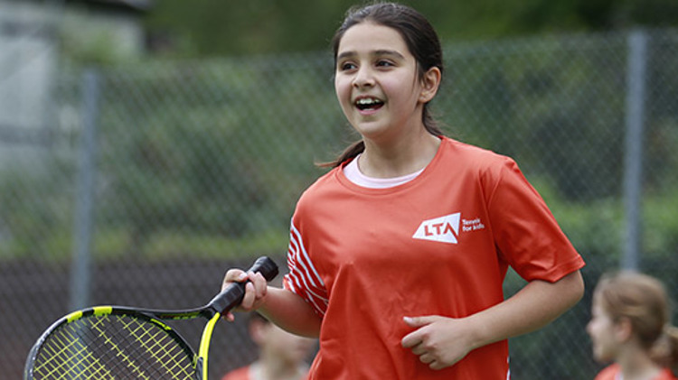 junior player on courting holding racket wearing a red LTA tennis top
