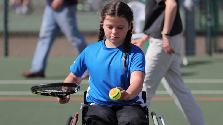 Young girl in wheelchair playing with her racket and ball